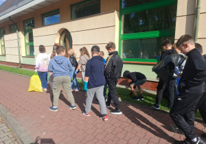 uczniowie w czasie sprzątania terenu wokół szkoły