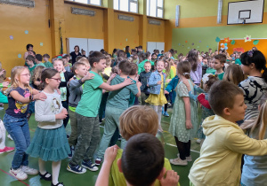 Uczniowie tańczą w korowodzie.