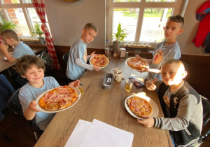 Czterej uczniowie prezentują swoje pizze.