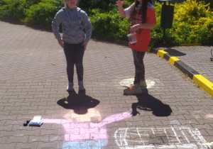 Dzieci prezentują rysunku wykonane kredą na chodniku