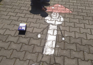 Chłopiec maluje kredą muchomora na chodniku