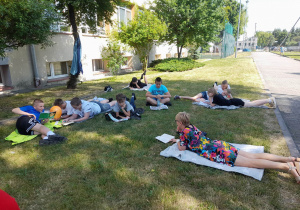 uczniowie klasy 6c wraz z nauczycielką języka polskiego czytaja ksiażki na pikniku czytelniczym