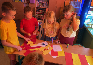 Uczniowie wykonują żółto-czerwone flagi województwa i regionu