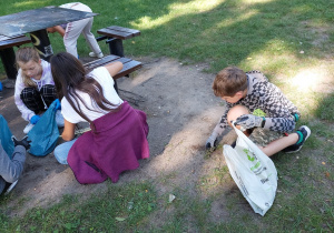 uczniowie w trakcie sprzątania terenu z niedopałków i kapsli