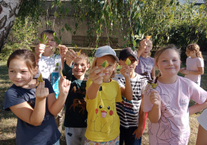 Grupa uczniów pokazuje jesienne liście