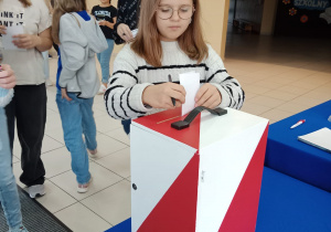 Dziewczynka wrzuca kartę wyborczą do urny