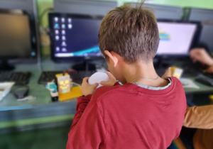 Chłopiec skupiony na budowaniu urządzenia z klockó LEGO, w tle monitor z instrukcjami.