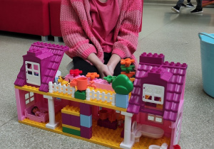Dziewczynka prezentuje zbudowany z klocków domek