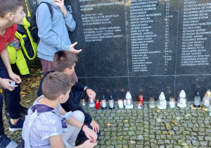 uczniowie składają znicze pod pomnikiem osób zamordowanych w obozie przesiedleńczym w Konstantynowie Łódzkim