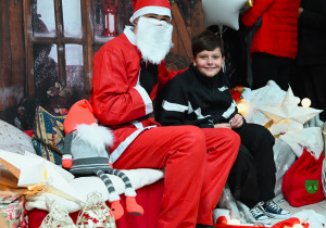 Chłopiec z Mikołajem na tle świątecznych dekoracji.