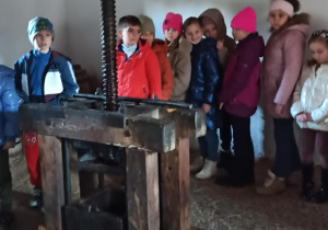 Uczniowie stoją przy urządzeniu do produkcji oleju.