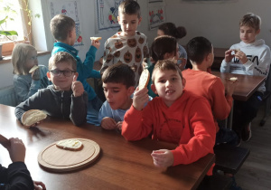 Uczniowie jedzą chleb z masłem.