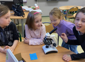 Dziewczynki oglądają preparat pod mikroskopem.