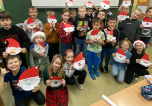 Zbiorowe zdjęcie uczniów z papierowymi Mikołajami- pracami, które wykonali.
