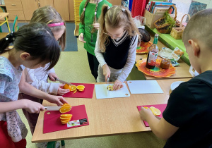 Dzieci kroją na deskach pomarańcze, cytryny, imbir.