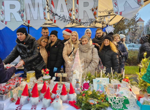 Zbiorowe zdjęcie rodziców i nauczycieli pracujących na świątecznym stoisku.