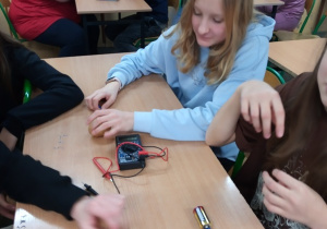 Uczniowie mierzą napięcie elektryczne zbudowanej przez siebie baterii.