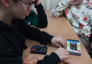 Uczniowie mierzą napięcie elektryczne zbudowanej przez siebie baterii.