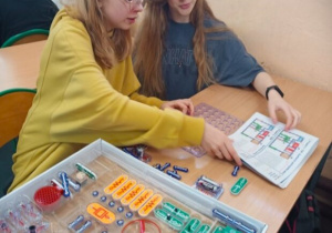 Dwie dziewczynki analizują schemat obwodu elektrycznego przed zbudowaniem go.