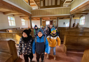 Uczniowie we wnętrzu drewnianego kościółka.