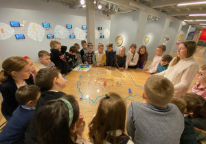 Uczniowie stoją wokoło szkicu prezentującego Łódź na przestrzeni lat.