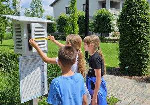 Uczniowie mierzą drzwi stacji meteorologicznej.