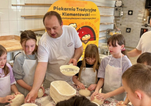 Uczniowie formują bochenki chleba.