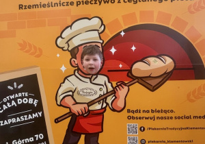 Uczeń na okolicznościowej ściance piekarni.