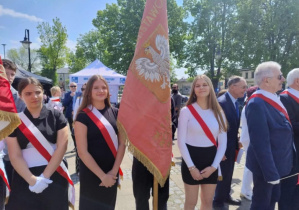 uczniowie stoją na placu ze sztandarem.