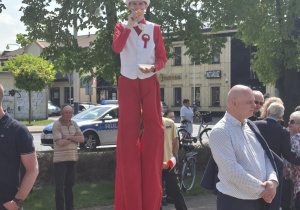 szczudlarz rozdający flagi