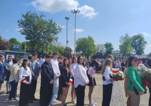 uczniowie składający kwiaty pod pomnikiem