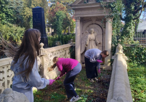 uczennice porządkują grób na Starym Cmentarzu w Łodzi