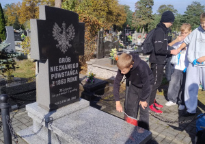 Grób Nieznanego Powstańca z 1863 r. i uczniowie w czasie porządkowania grobu
