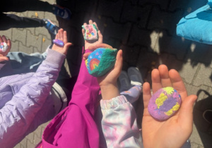 Dłonie uczniów z pomalowanymi kamieniami 1