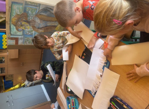 Uczniowie nacinają białe kartki papieru.