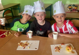 Uczniowie w kucharskich czapkach piją przygotowaną owocową herbatę