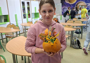 uczennica pokazuję swoją jesienną kompozycję w dyni.