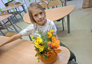 uczeń prezentuje swoją ozdobioną kwiatami dynie