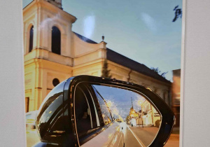 fotografia ukazująca miasto w odbiciu lusterka samochodu – nowoczesne spojrzenie na tradycję i historię.