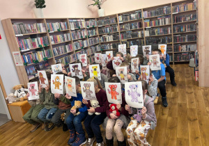 zdjęcie grupowe uczniów w bibliotece, uczniowie trzymaja w rękach malowanki z misiami