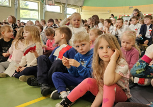 uczniowie klas 1-3 podczas uroczystego apelu z biało-czerwonymi flagami