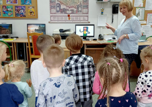 Dzieci stoją przed komputerem i patrzą na sygnalizator wyświetlany na ekranie komputera.