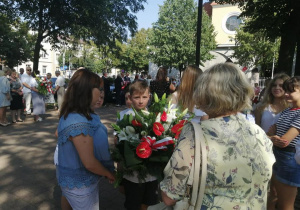 Uczniowie wręczają kwiaty pod tablicą pamiątkową upamiętniającą mieszkańców Konstantynowia Łódzkiego zamordowanych podczas II wojny światowej.