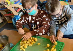 Uczniowie kroją ziemniaki na ćwiartki.