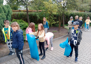 Dzieci sprzątają teren wokół szkoły