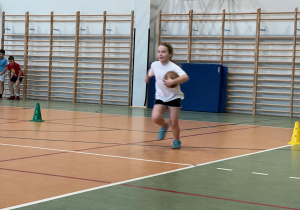 Uczennica biegnie z piłką.