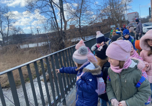Uczniowie stoją na mostku nad rzeką Dobrzynką