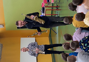 Muzycy prezentują instrumenty dęte- trąbkę i saksofon.