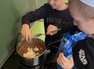 Dwóch chłopców gotuje czekoladę na kuchence indukcyjnej.