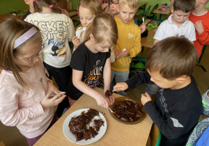 Uczniowie nabierają na łyżeczki przygotowaną przez siebie czekoladę.